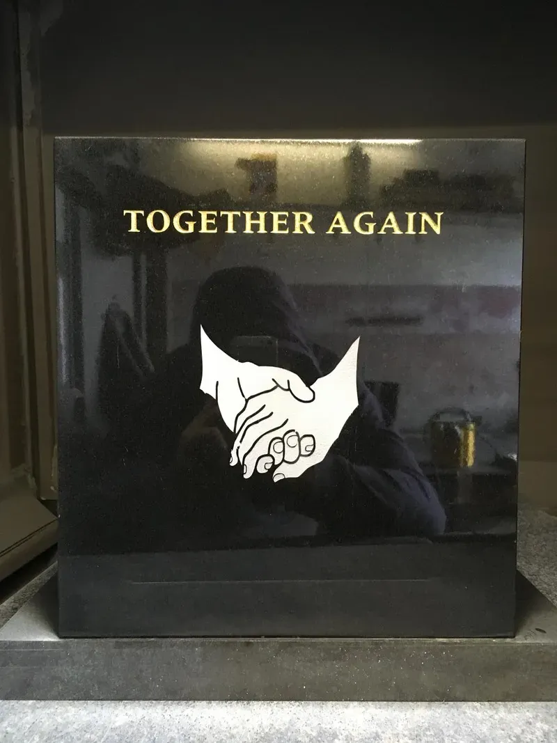 Polished black granite cremation tablet with an etched clasped hands motif, photographed in the FR Terrazzo workshop